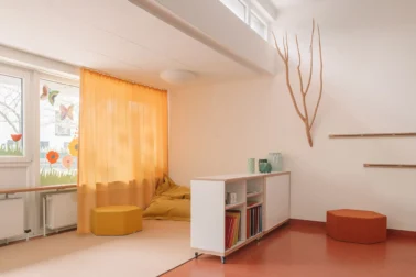 Rueckzugsnische im Gruppenraum Kindergartenmöbel und Raumgestaltung: Rückzugsnische im Gruppenraum mit Teppich und Sitzsack, ideal zum Spielen und Lesen in gemütlicher Atmosphäre.